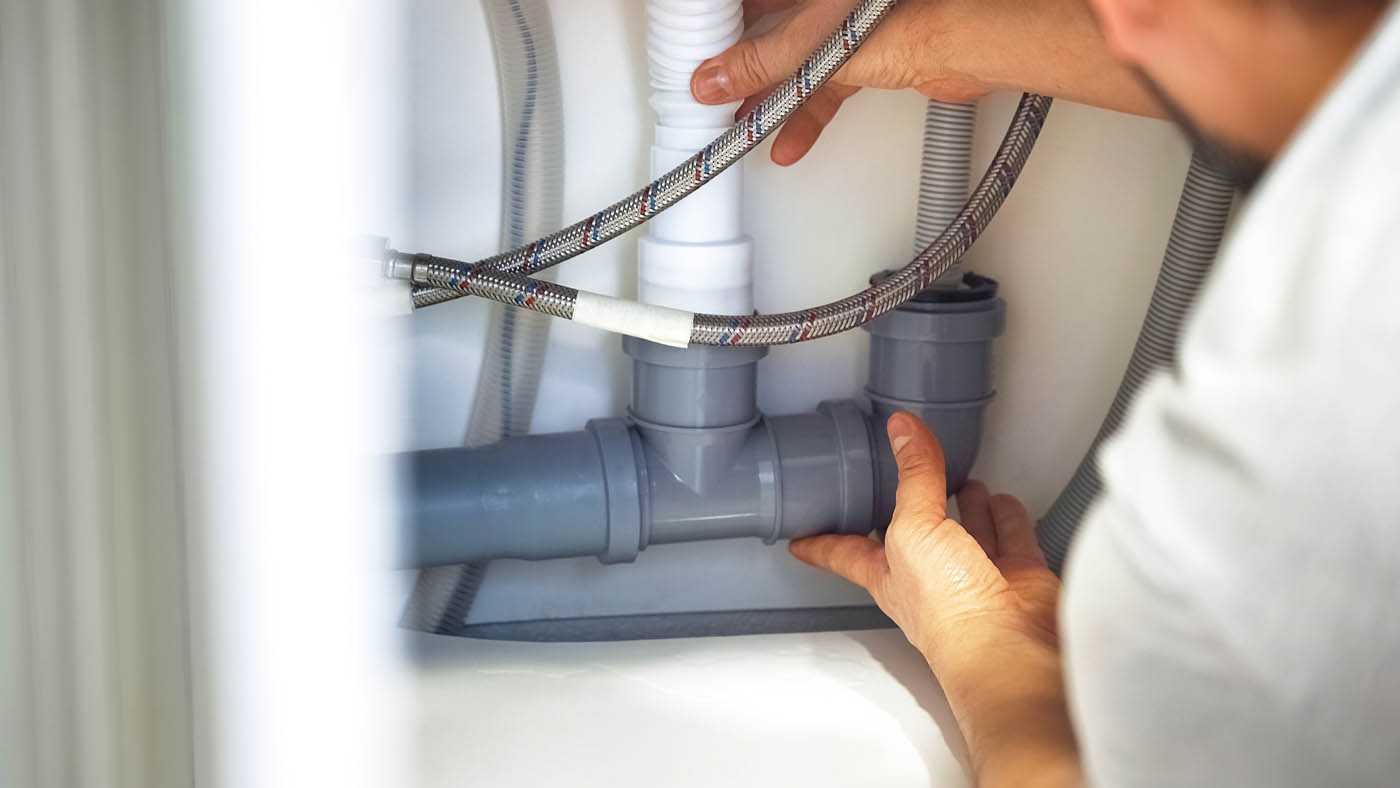 A plumber working under a sink - trust Zest Plumbing & Drain for all your plumbing needs in Arizona.