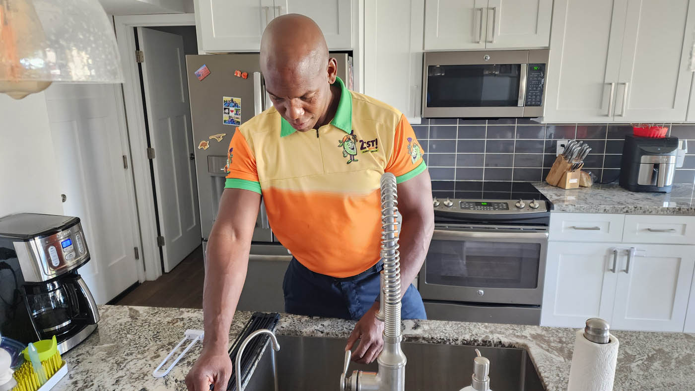 A Zest Plumbing & Drain technician working on a residential home kitchen sink, we are the top leak detection company in Scottsdale, AZ.